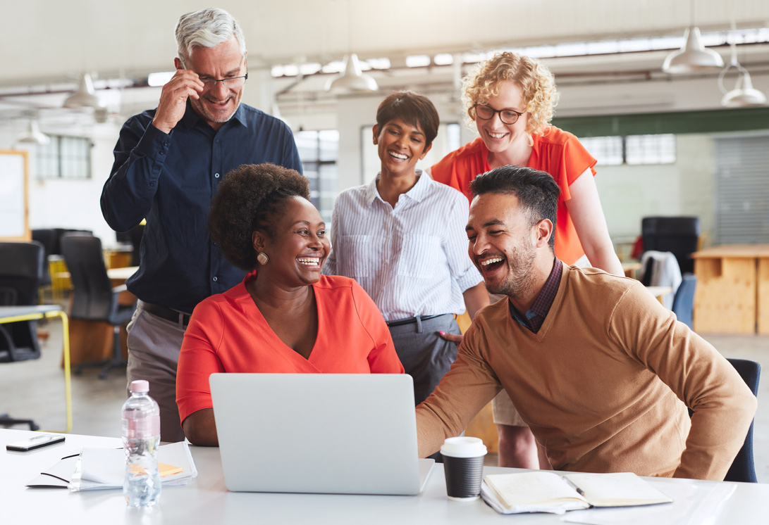 Laughing team of diverse businesspeople working together on a laptop